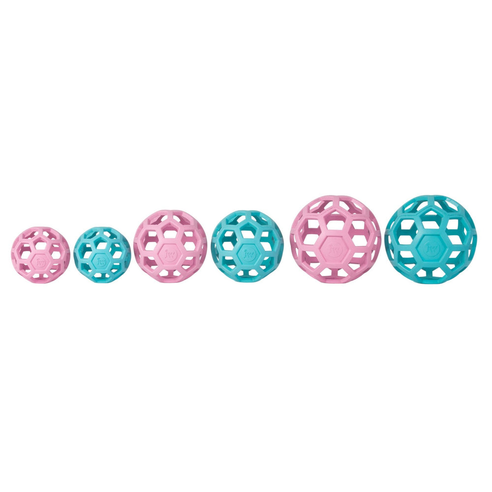 Six JW Hol-EE Roller Trend-EE puzzle balls line up, increasing in size left to right. They alternate colors, starting with light pink and teal. Crafted from natural rubber by Jw, their geometric lattice design ensures mental stimulation.