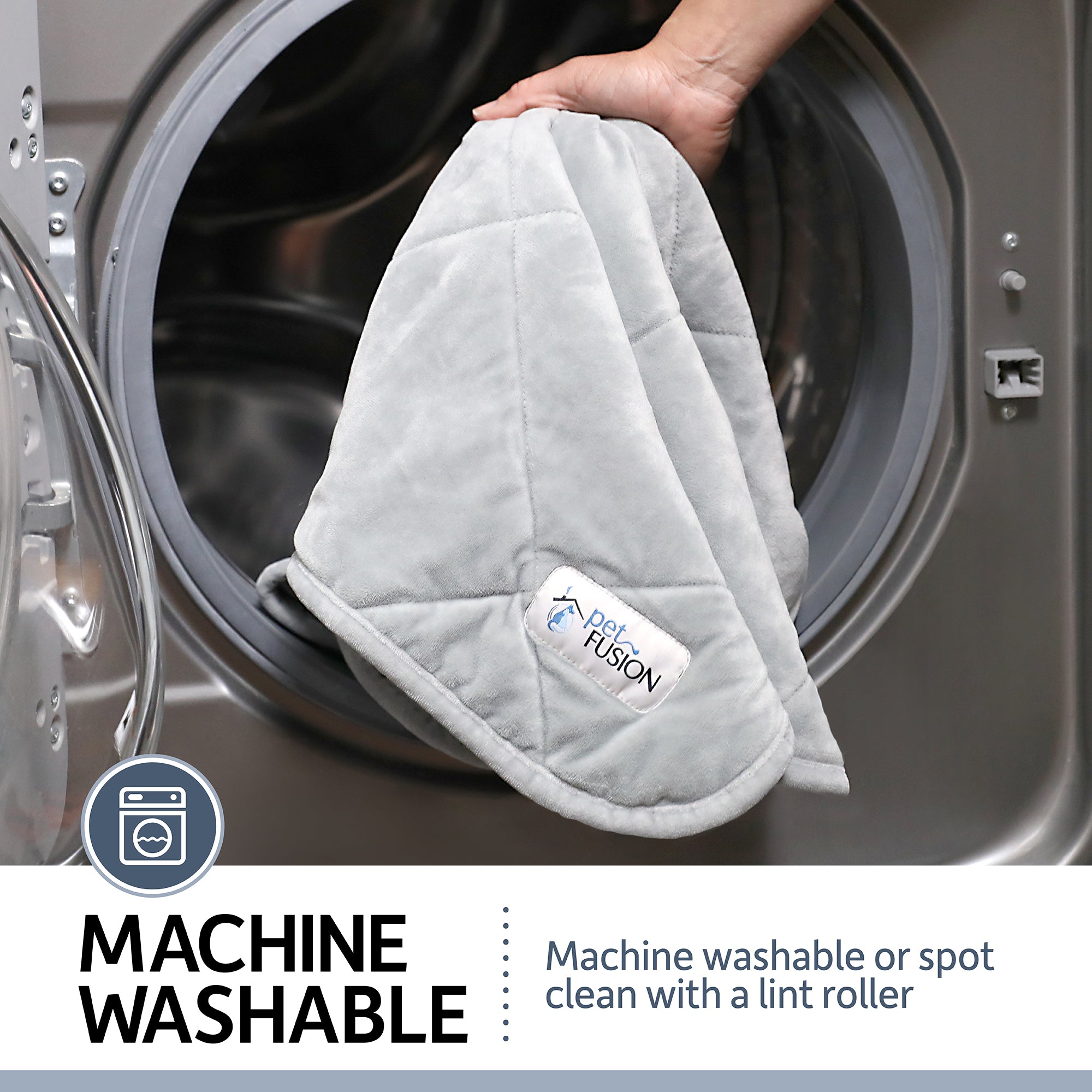 A hand places a PetFusion Microplush Quilted Dog Blanket into a washing machine. Text: MACHINE WASHABLE – easily refresh the ultra-soft blanket by machine washing or spot cleaning with a lint roller, shown with a washing machine icon.