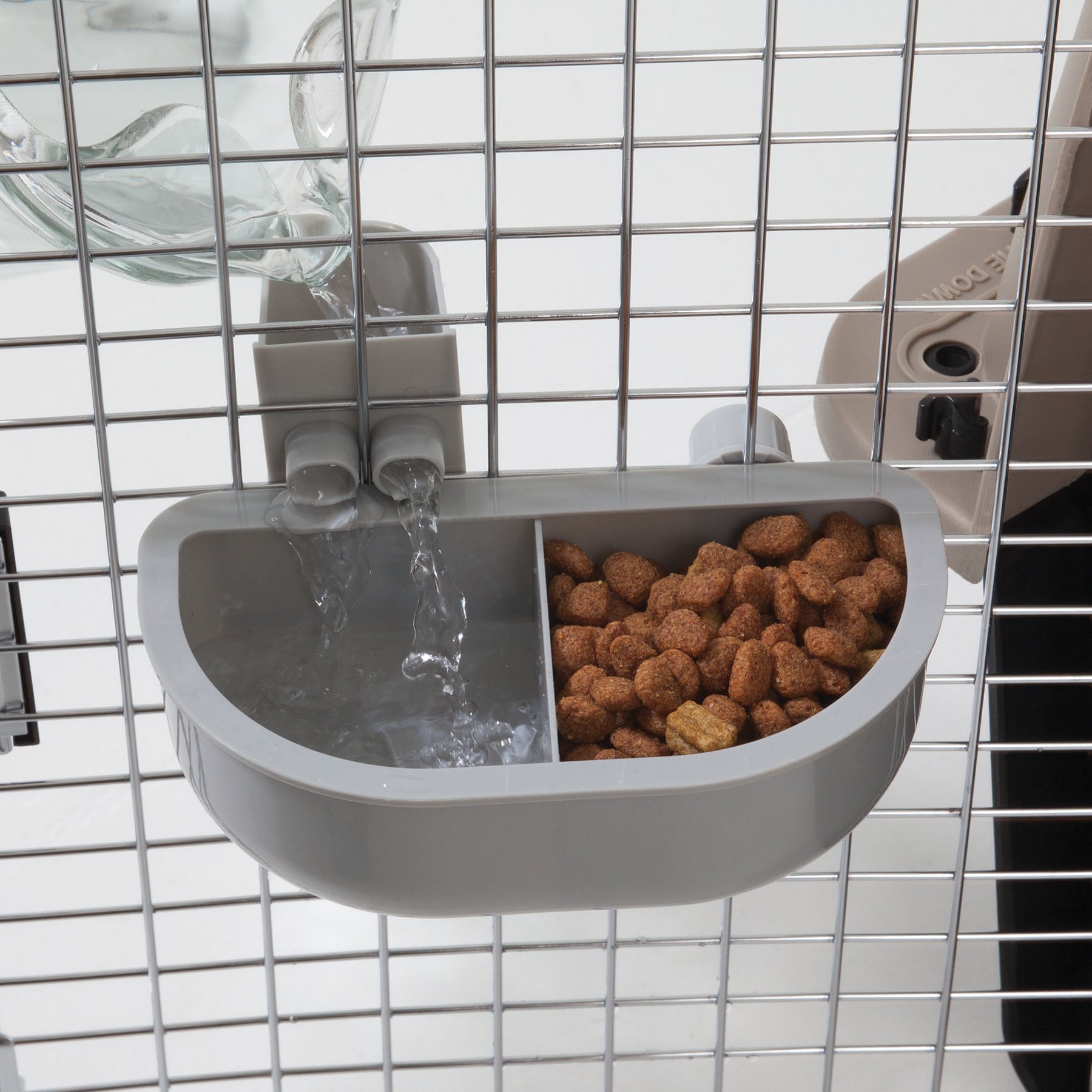 The Petmate No Spill Kennel Cup Double Diner by Petmate attaches to pet cage bars, featuring a dual feeder with one section for water from a connected bottle and another for kibble. Its BPA and lead-free, ensuring your pets safety.