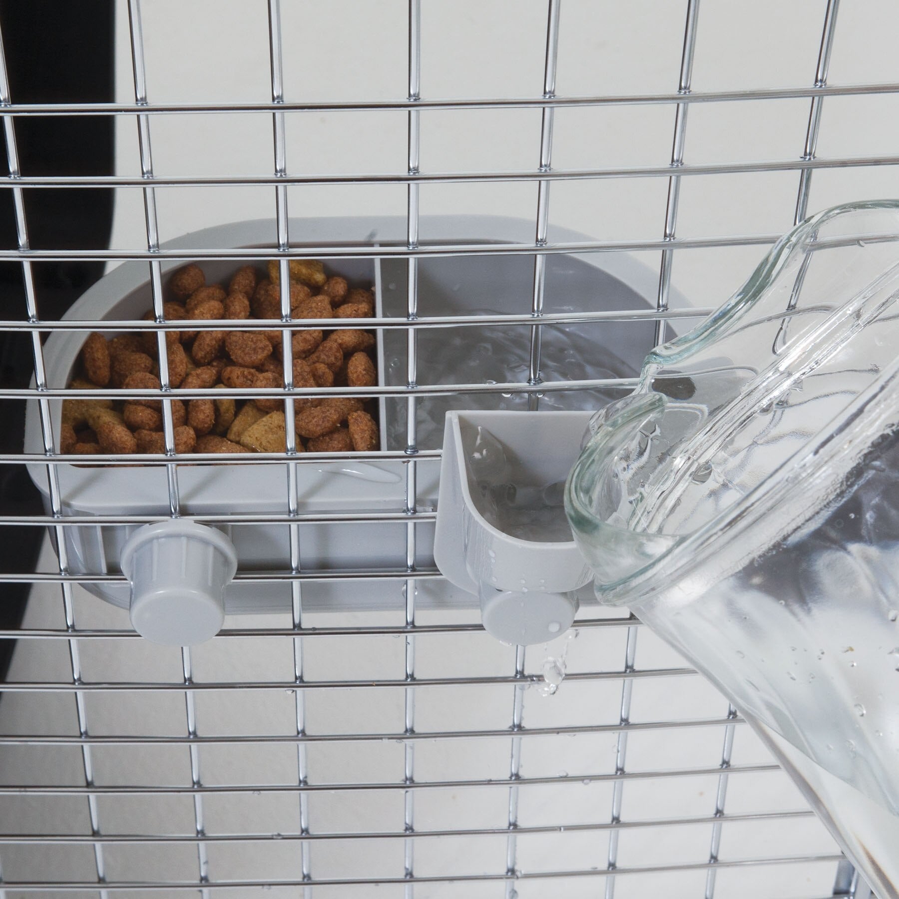 The Petmate No Spill Kennel Cup Double Diner provides hydration and nourishment to pets in metal cages, featuring a water pitcher for easy filling and a feeding tray for brown pet food. This setup ensures pets stay nourished and hydrated on the go with BPA and lead-free materials.