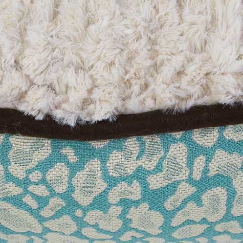 The Petmate Two-Sided Fashion Dog Pillow Bed features a close-up fabric detail: white fluffy texture atop a dark brown strip, with turquoise fabric showcasing a light beige leopard print below, all in a cozy, washable design.