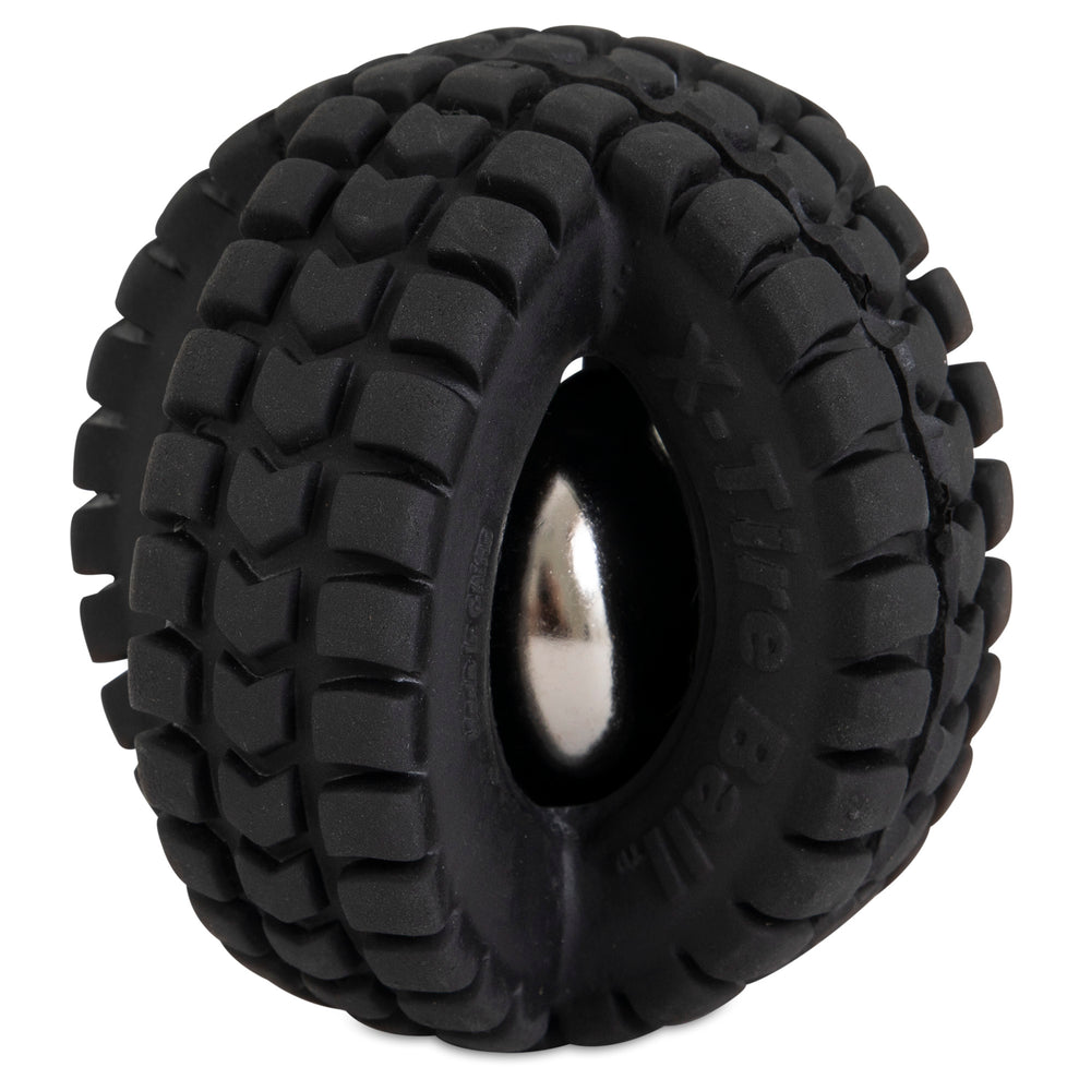Close-up of the Pet Qwerks Jingle X-Tire Ball, a black rubber dog toy by Petqwerks, resembling a thick tire with rugged tread. A metallic jingle ball is embedded and visible through the open space, set against a plain white background.